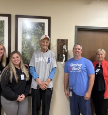 GH staff with Scott by the cancer bell donated by his family