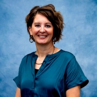 Headshot of Maria in blue dress shirt